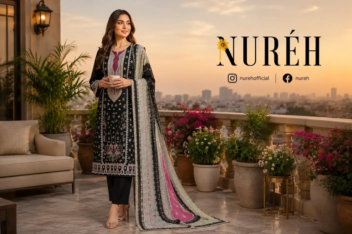 A woman stands on a rooftop terrace wearing a traditional embroidered outfit with a long black kurta, black trousers, and a matching dupatta with pink and gray patterns. The background shows a city skyline at sunset with potted plants and the brand name NURÉH displayed on the right.
