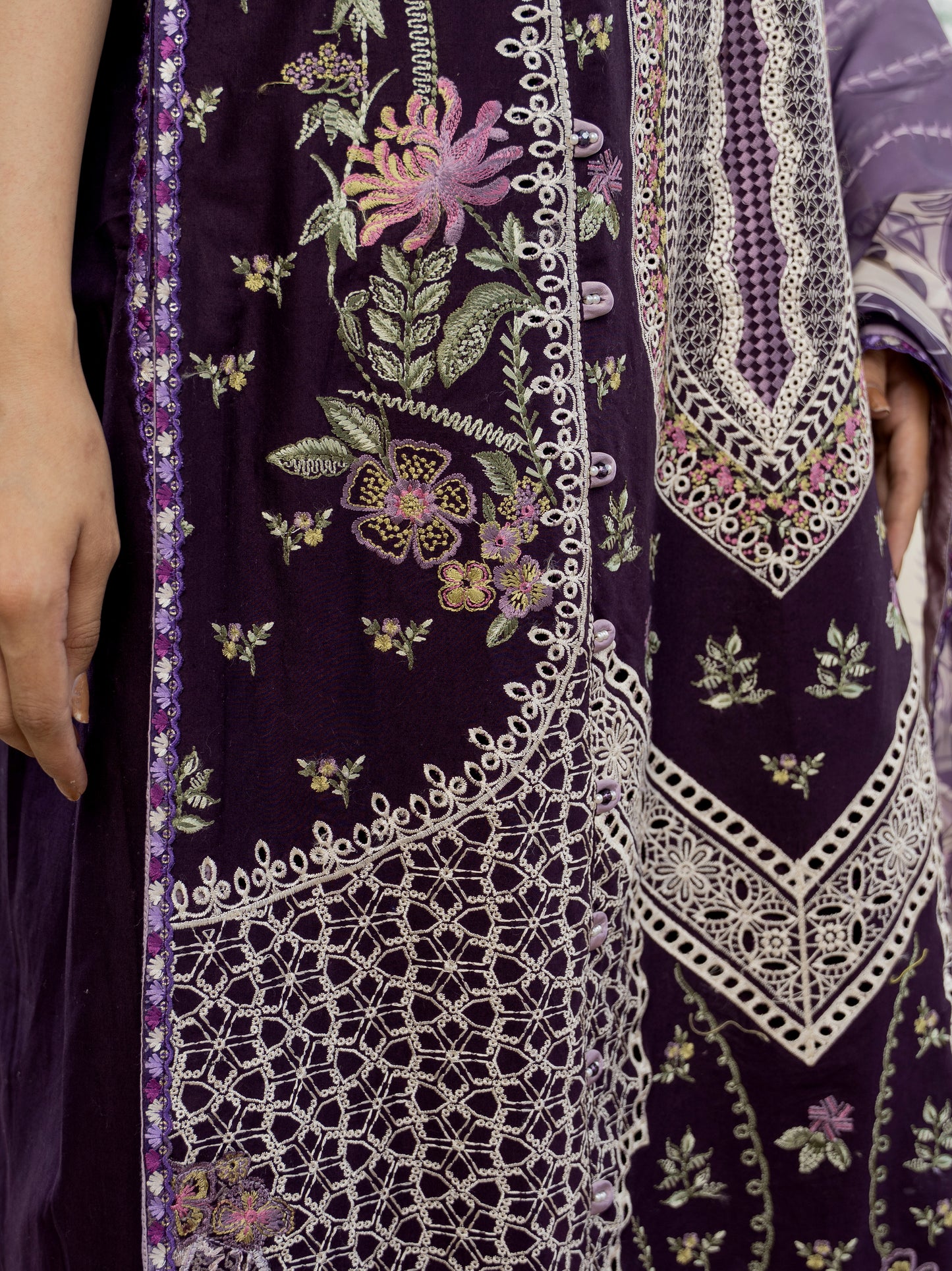 Close-up of a dark purple fabric with intricate white embroidery and floral patterns.