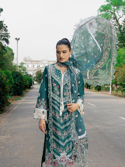 Woman in traditional green and white embroidered outfit holding a decorative parasol outdoors.