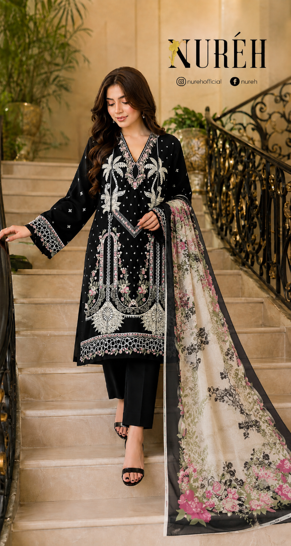 A woman wearing a black embroidered kurta with silver detailing and a floral printed dupatta, walking down an indoor staircase. The brand name 'NURÉH' is visible at the top right.