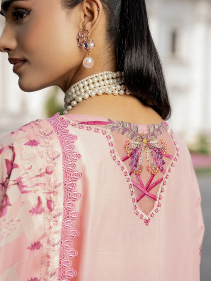 Close-up back view of a woman wearing a light pink embroidered kurta with floral print, a pearl necklace, and earrings, set against a softly blurred outdoor background.
